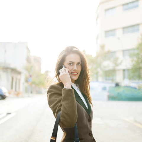 Junge Frau im Freien mit Mobiltelefon, lizenzfreies Stockfoto