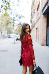 Schöne junge Frau in rotem Kleid mit Einkaufstüten - VABF00922