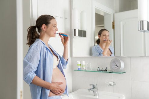 Schwangere Frau im Badezimmer beim Zähneputzen - DIGF01496
