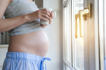 Close-up of pregnant woman holding cup at the window - DIGF01503