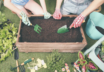 Couple preparing soil to plant vegetables in the container of their urban garden - RTBF00575