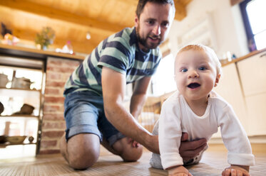 Vater unterstützt krabbelndes Baby zu Hause - HAPF01213