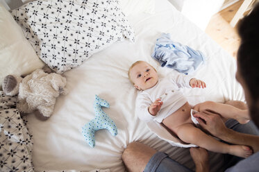 Father changing baby's diapers on bed - HAPF01217
