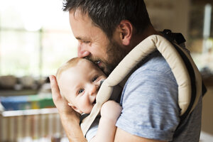 Glücklicher Vater mit Baby im Tragesitz zu Hause - HAPF01227