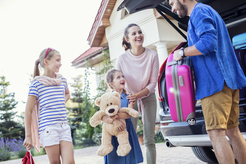 Happy family packing car for vacation stock photo