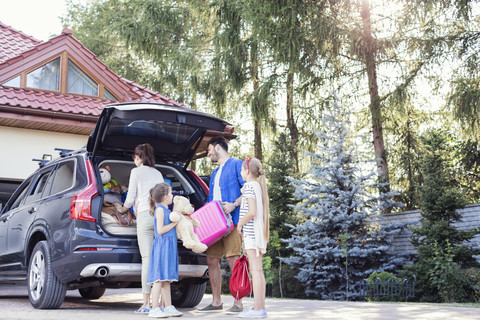 Glückliche Familie packt Auto für Urlaub, lizenzfreies Stockfoto