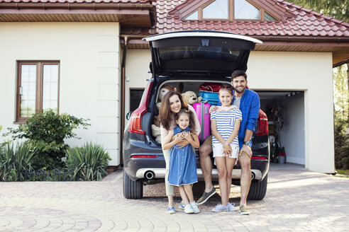 Glückliche Familie vor einem für den Urlaub gepackten Auto - WEST22306