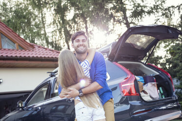 Father and daughter embracing in front of their car - WEST22323