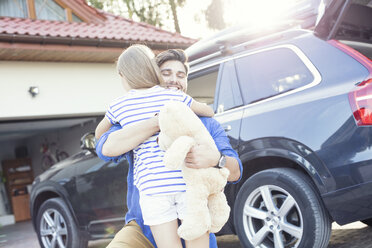 Father and daughter embracing in front of their car - WEST22324