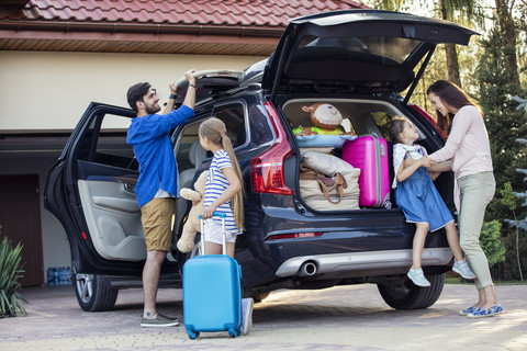 Glückliche Familie packt Auto für Urlaub, lizenzfreies Stockfoto