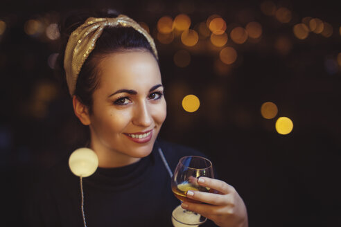 Portrait of smiling woman with drink wearing golden hair-band - LCUF00085