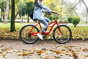 Junge Frau fährt mit dem Fahrrad in einem Park - MGOF02695