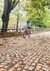 Glückliche junge Frau auf dem Fahrrad in einem Park - MGOF02709