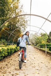 Lächelnde junge Frau auf dem Fahrrad in einem Park - MGOF02710