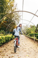 Smiling young woman riding a bike in a park - MGOF02710