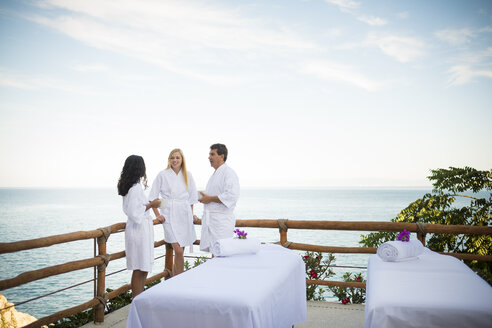 Urlaubsgäste, die auf der Terrasse eines luxuriösen Ferienresorts am Meer auf ihre Massage im Freien warten - ABAF02106