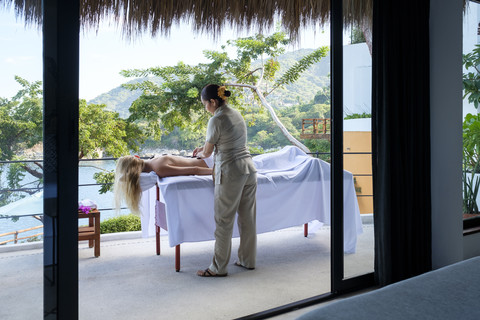 Young woman receiving a massage on the balcony of her suite in a luxury vacation retreat stock photo