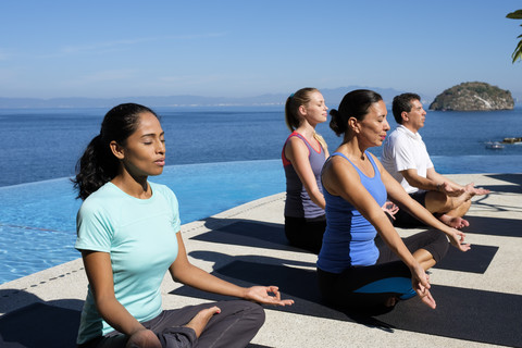 Yoga-Gruppe übt in einem Resort am Meer, lizenzfreies Stockfoto