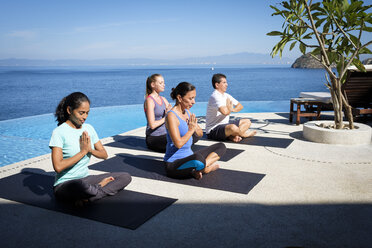 Yoga group exercising at ocean front resort - ABAF02110