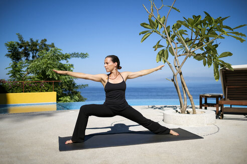 Frau übt Yoga in einem Resort am Meer - ABAF02115