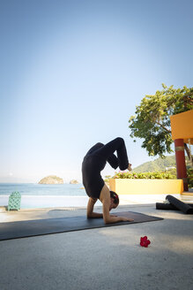 Frau übt Yoga in einem Resort am Meer - ABAF02121