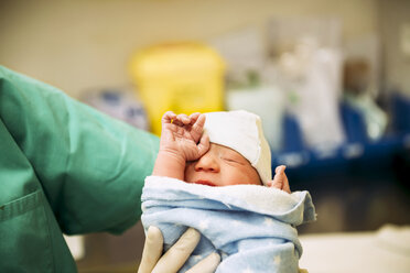 Neugeborenes Mädchen, eingewickelt in ein Handtuch, gehalten vom Arzt im Kreißsaal - GEMF01301