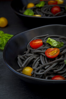 Schüssel mit Spaghetti al Nero di Seppia mit Tomaten und Basilikumblättern, Nahaufnahme - LVF05718