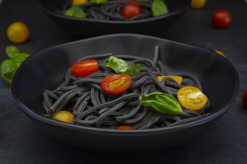 Schüssel mit Spaghetti al Nero di Seppia mit Tomaten und Basilikumblättern, Nahaufnahme - LVF05719