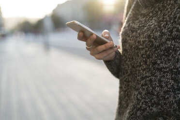 Woman using cell phone outdoors - KKAF00194