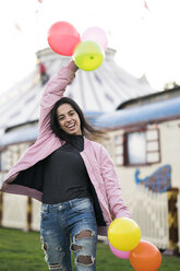 Happy young woman holding balloons outdoors - KKAF00204