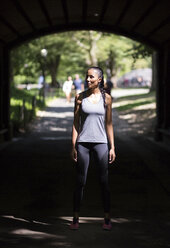 Female athlete standing in underpass in park - GIOF01697