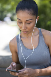 Female athlete listening to music with smartphone - GIOF01699