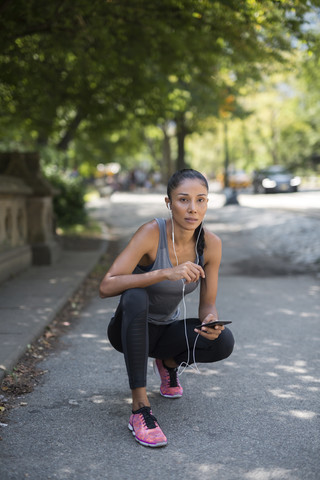 Sportlerin hört Musik mit Smartphone, lizenzfreies Stockfoto