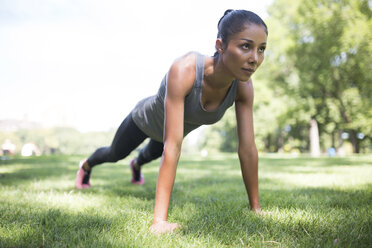 Woman doing push-ups on meadow in park - GIOF01705