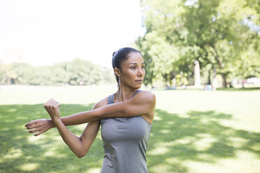 Woman stretching on meadow in park - GIOF01707