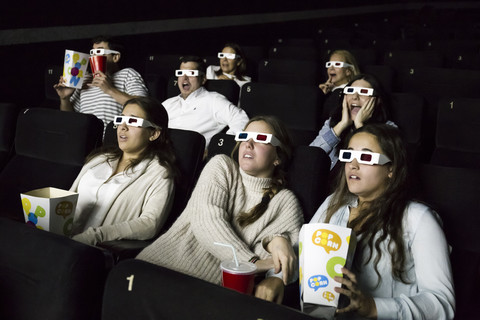Verängstigte Menschen mit 3D-Brillen, die sich einen Film im Kino ansehen, lizenzfreies Stockfoto