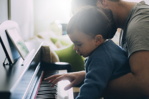 Child and his father playing piano stock photo