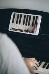 Mann lernt Klavierspielen mit Videotutorial auf einem Tablet - JPSF00031