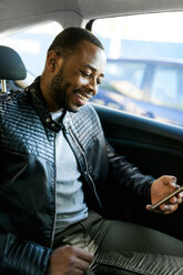 Junger Mann benutzt Smartphone im Taxi - VABF00928