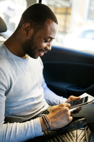 Junger Mann benutzt Smartphone im Taxi, lizenzfreies Stockfoto