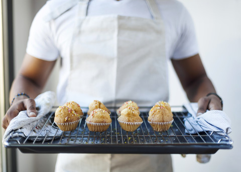 Mann hält Tablett mit Muffins, lizenzfreies Stockfoto