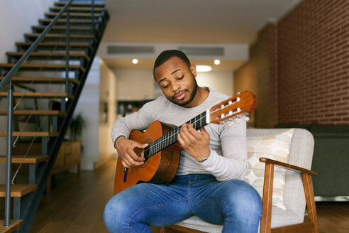 Young man at home playing guitar - VABF00956