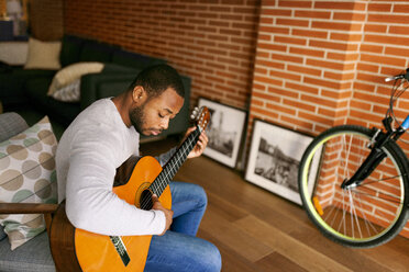 Junger Mann spielt zu Hause Gitarre - VABF00957