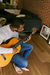 Junger Mann spielt zu Hause Gitarre - VABF00958