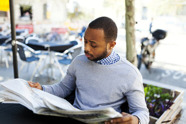 Junger Mann liest Zeitung in einem Straßencafé - VABF00963