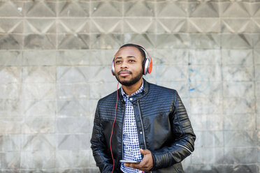 Junger Mann mit Kopfhörern und Smartphone - VABF00971