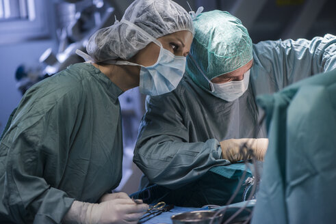 Neurochirurg mit Krankenschwester beim Schließen der Operationswunde - MWEF00107