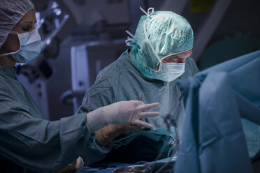 Neurochirurg mit Krankenschwester beim Schließen der Operationswunde - MWEF00108