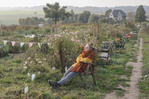 Young woman relaxing in cottage garden - KNSF00717