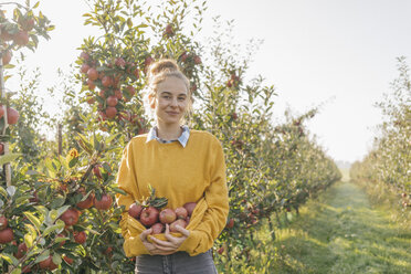 Young woman holding apples in orchard - KNSF00737